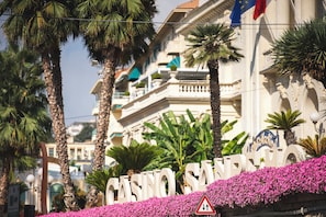 Experience the grandeur of Casino San Remo, marked by a classical entrance with ornate detailing and lush greenery.