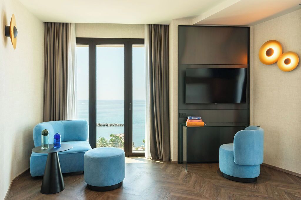 Un salon moderne doté d’un grand téléviseur, d’un canapé, d’une table basse et offrant une vue sur la mer.