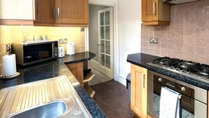 Una cocina con gabinetes de madera, microondas, estufa y lavamanos.