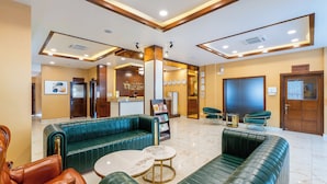 Un hall con sofás de cuero verde, un mostrador de recepción y un cartel que indica Indreni Hall.
