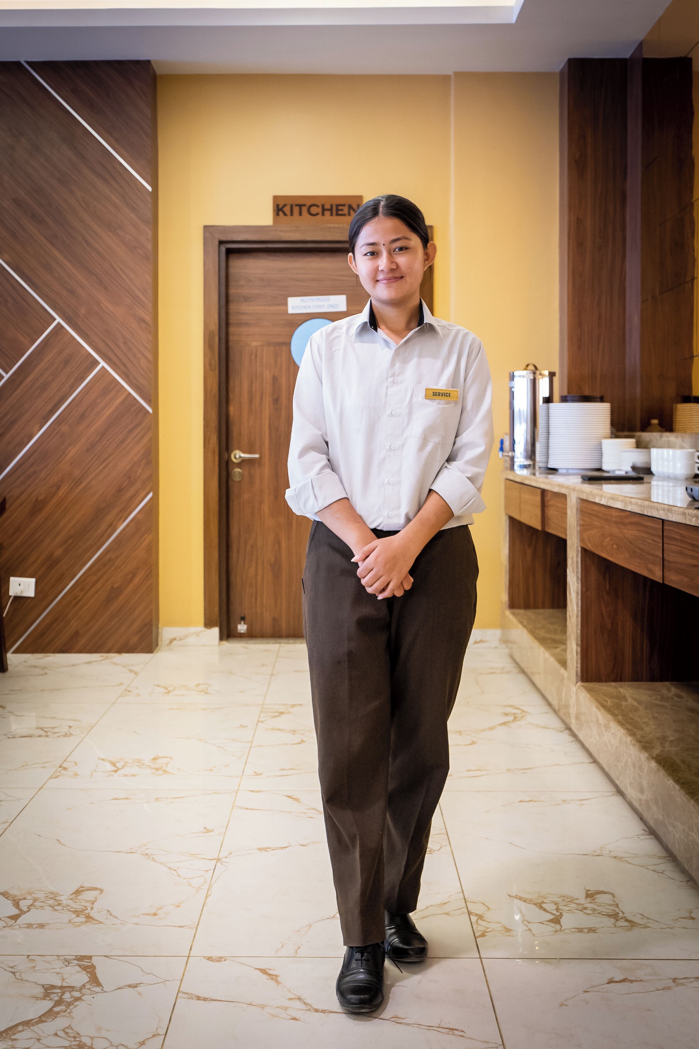 A person standing in a hallway with a sign above a door that reads "KITCHEN".