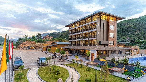 Un hotel de varios pisos con piscina, un jardín ajardinado y un estacionamiento.