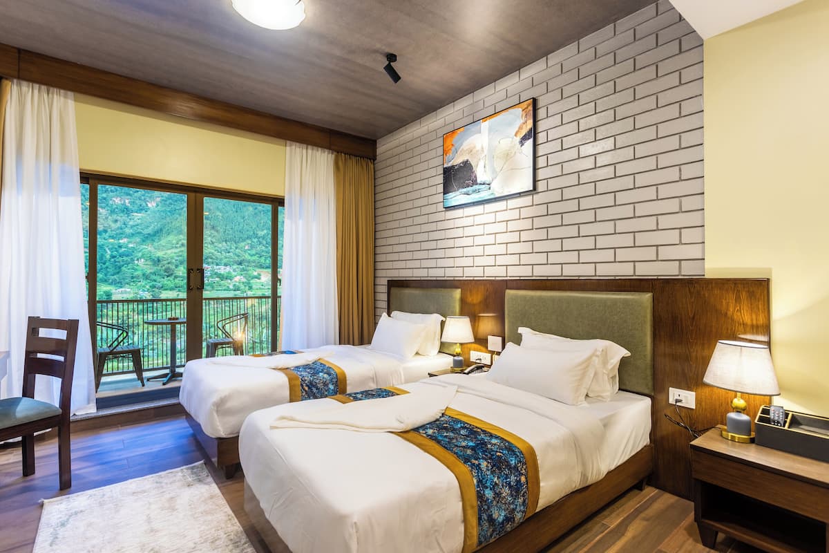 Habitación de hotel con dos camas, un balcón con vistas al follaje y una cabecera de madera, además de un cuadro en la pared.