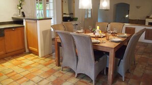 A dining area with a wooden table set for four, surrounded by wicker chairs. There is a small kitchen area with a refrigerator and a counter. - 10 persons accommodation: spacious 6 pers villa + 4pers Cabanon in Aups (Provence) (Aups)