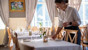 Een restaurant met een gedekte tafel, met een vaas met een bloem en een kaars.