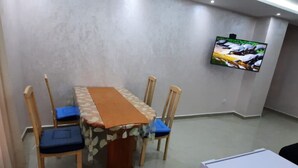 A conference room with a table, chairs, and a mounted TV. - 2-bedroom apartment for 6 people (Tanger)