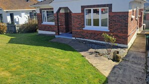 A two-story house with a brick facade and white trim, a small front yard, and a visible chimney. - Spacious, Affordable, Peaceful Family Home (Dunedin)