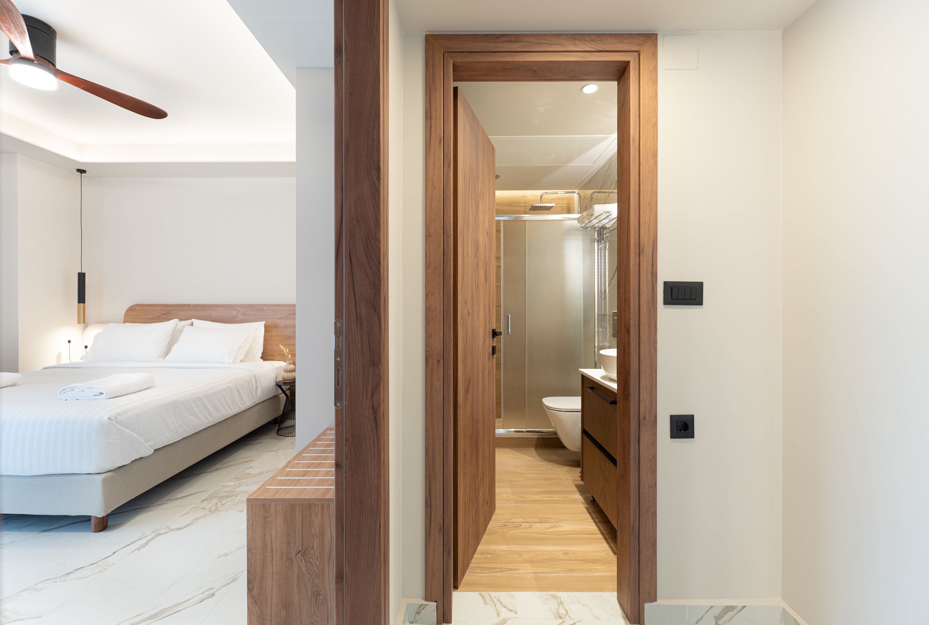 Quarto com cama, piso de madeira e ventilador de teto.