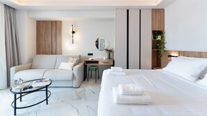 Une chambre d’hôtel moderne équipée d’un lit, d’un canapé, d’un bureau et d’une petite table.