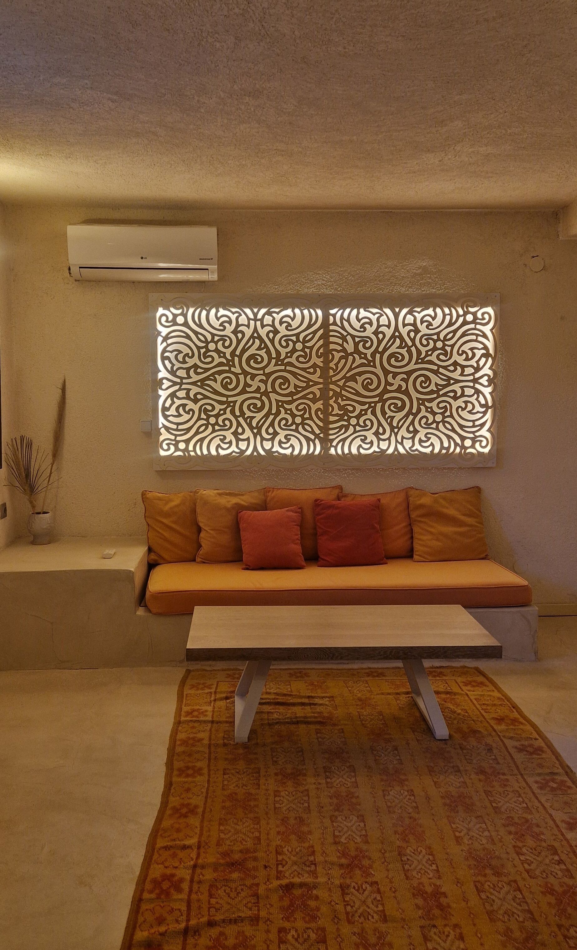A modern living room with a sofa, a patterned rug, and a decorative wall panel.
