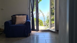 Una habitación con un sofá azul y vistas al verdor exterior.
