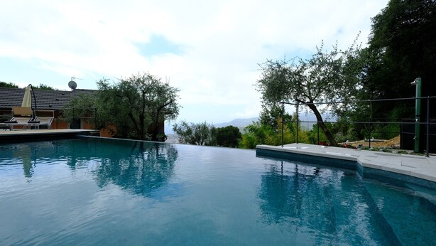 Una piscina con sillones de descanso y vistas a árboles y montañas al fondo.