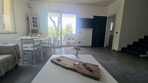 Una sala de estar moderna con comedor, escalera y vistas al exterior.