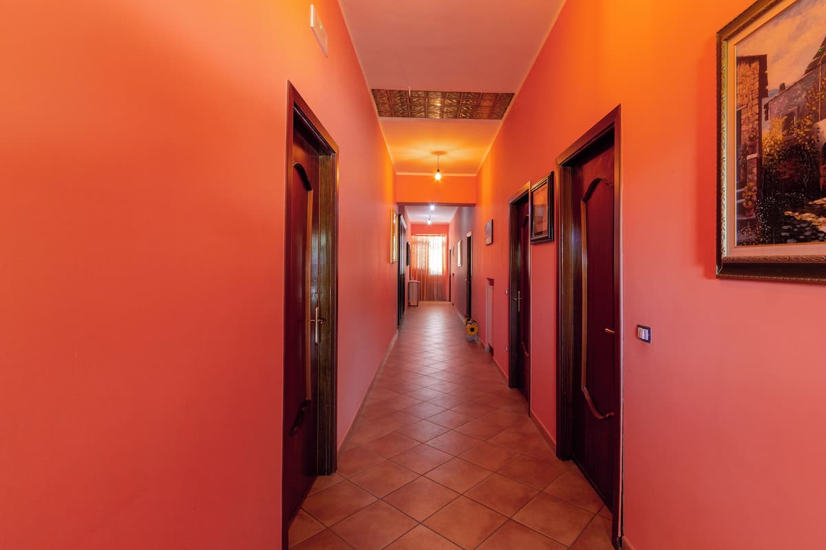 Un pasillo con puertas a ambos lados que conduce a una habitación con cama y ventana.