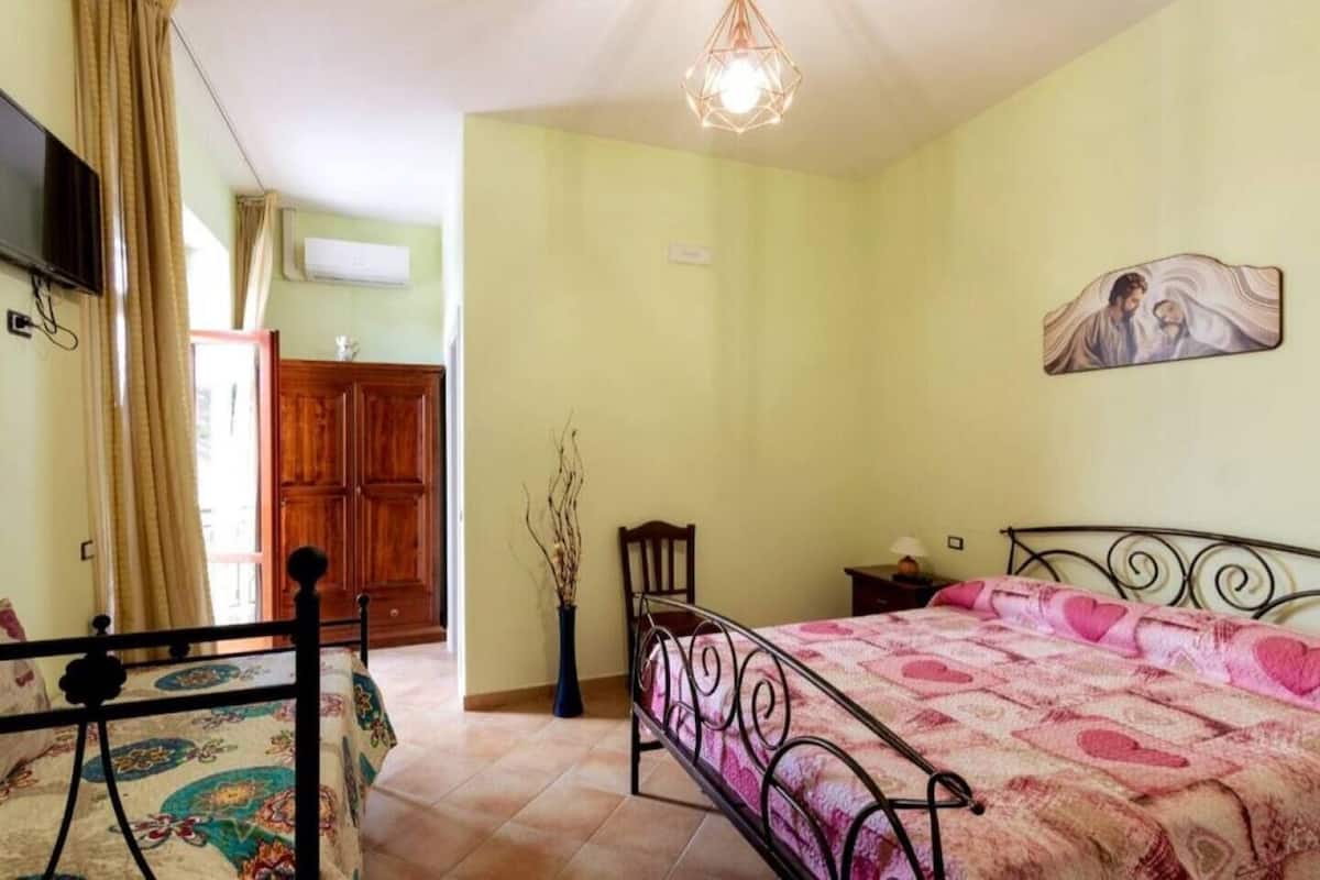 Un dormitorio con cama, mesita de noche, televisor y armario de madera.