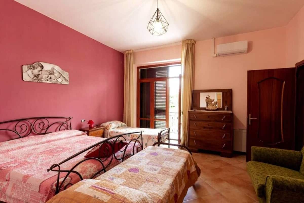 Un dormitorio con dos camas, un tocador, una silla y una puerta.