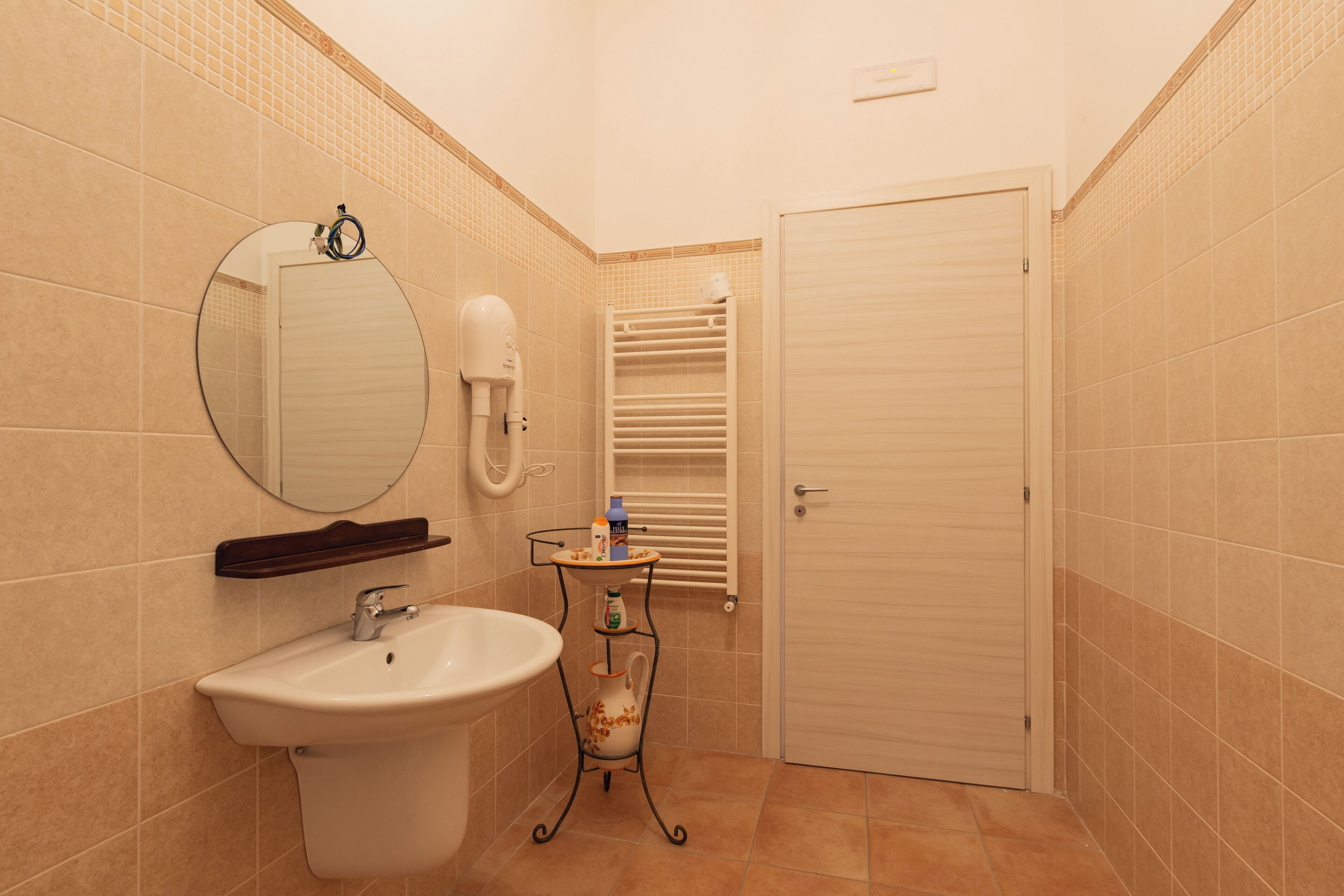 A bathroom with a sink, mirror, towel rack, and a door.
