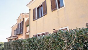 A building with multiple windows and balconies, surrounded by dense shrubbery. - Casa Graziosa - Appartamento 5 (Nurachi)