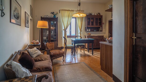 A cozy living room with a sofa, chairs, a dining table, and a kitchen area. - Residence Serliana (Montasola)