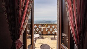 A room with a view of the mountains through a glass door, a table with chairs, and a patterned curtain. - Residence Serliana (Montasola)