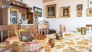 Un coin repas avec une nappe à motifs floraux, des meubles en bois et des œuvres d’art encadrées accrochées au mur.