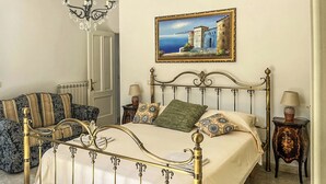 A bedroom with a four-poster bed, a painting on the wall, and a chandelier. - Hssoverato (Soverato)
