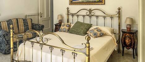 A bedroom with a four-poster bed, a painting on the wall, and a chandelier.