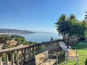 A balcony with a view of the sea, a palm tree, and two white chairs. - Hssoverato (Soverato)