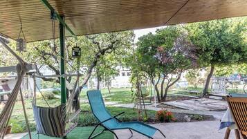 A hammock, a lounge chair, and a wooden bench under a wooden pergola.