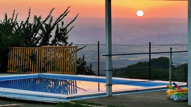Une piscine offrant une vue sur le coucher du soleil et le paysage lointain.