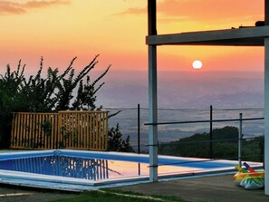 En pool med udsigt til solnedgang og det fjerne landskab.