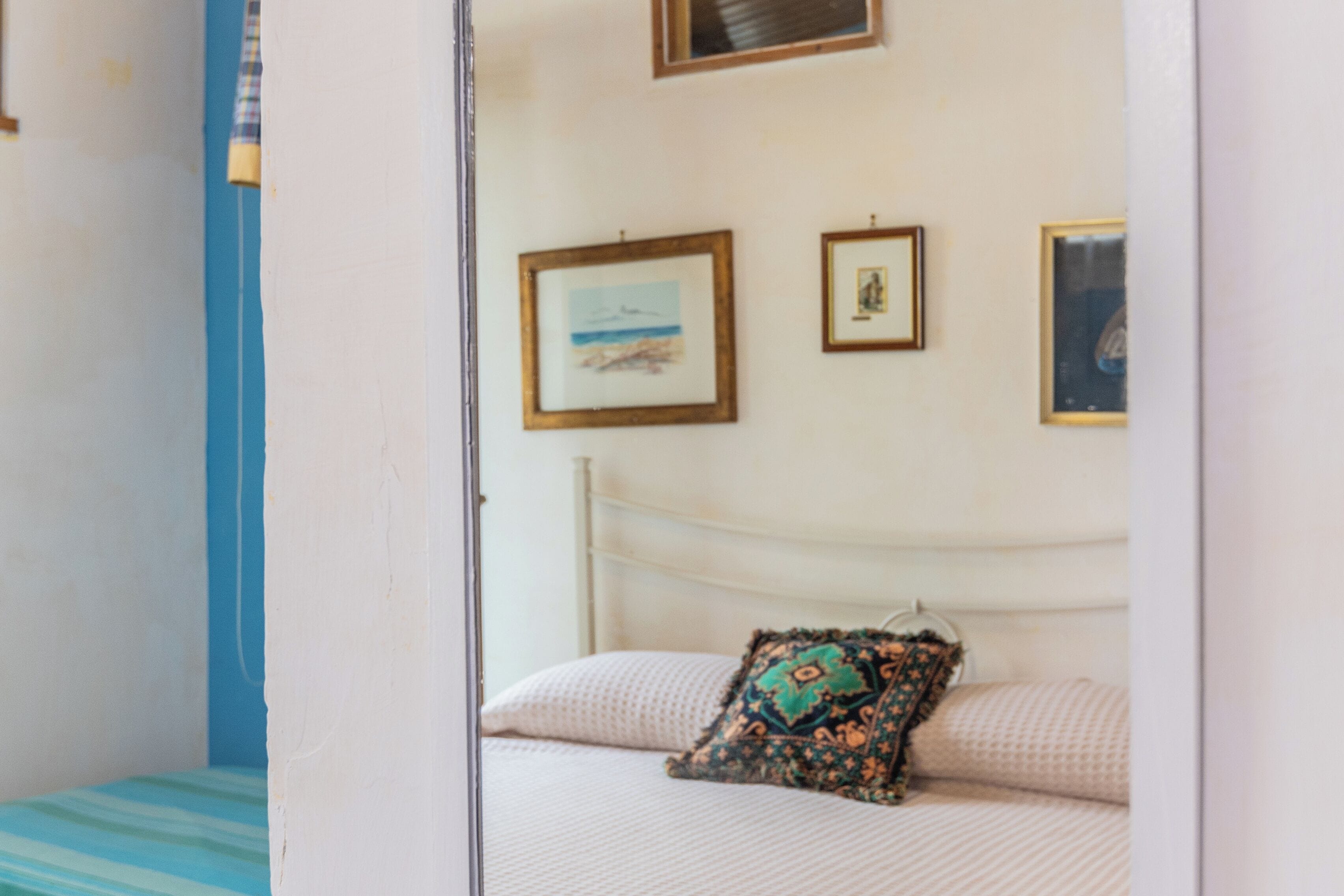 A bedroom with a bed, a pillow, and three framed pictures on the wall.
