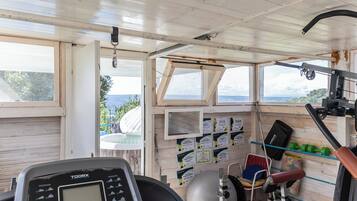 A gym with exercise equipment, a treadmill, and a wall with exercise program posters.