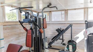 Een sportschool met diverse fitnessapparaten, waaronder een bank, krachttoestellen en een squatrek.