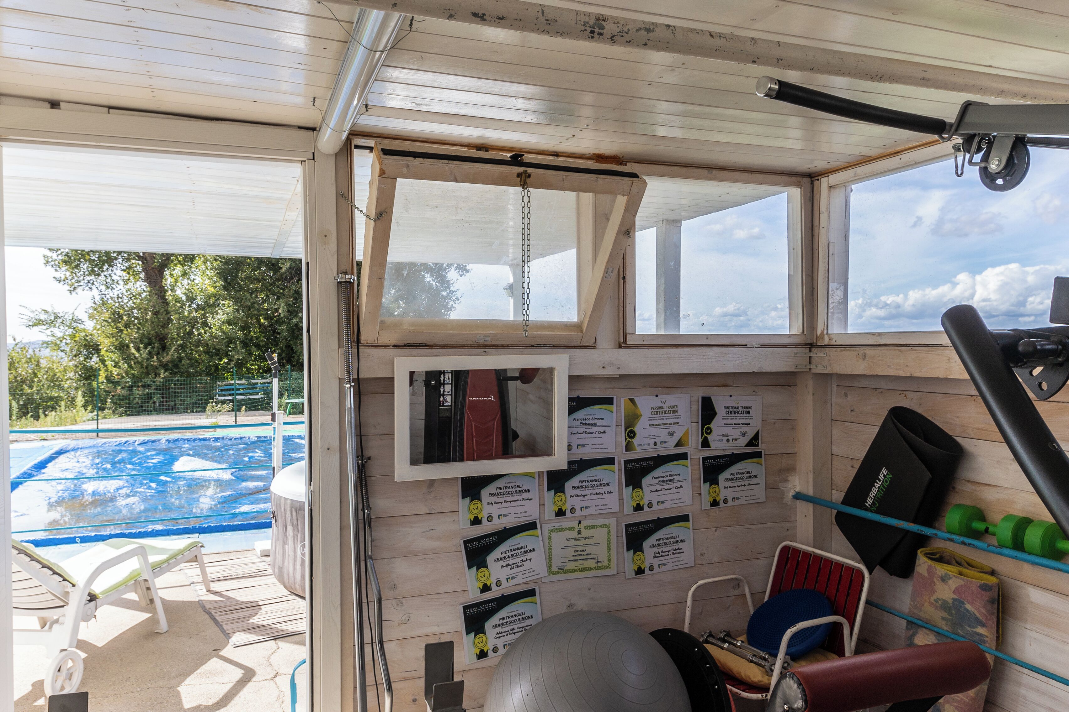 A room with a view of a swimming pool, exercise equipment, and informational cards on the wall.