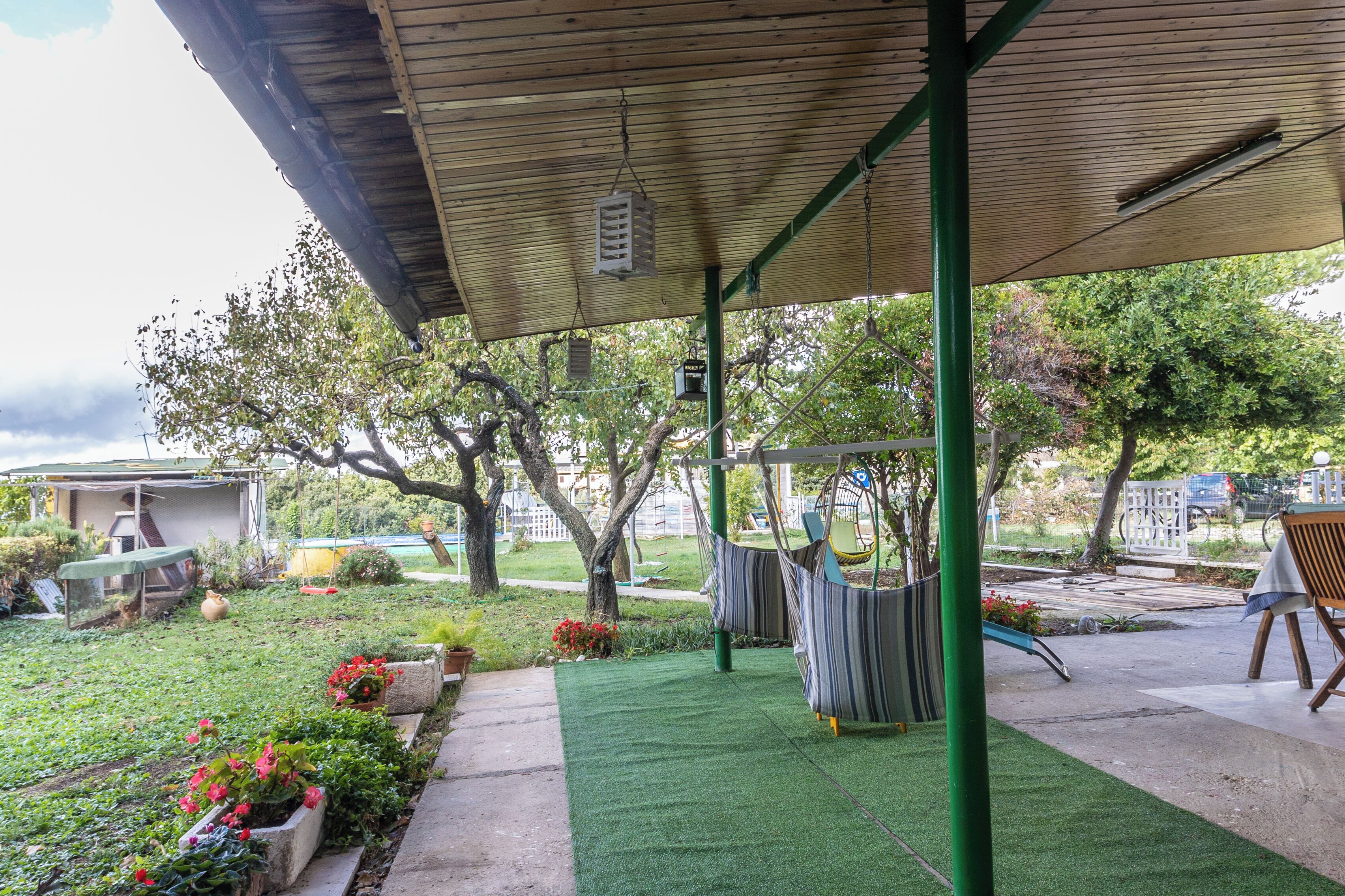Un espacio al aire libre cubierto con césped artificial, una hamaca y un conjunto de columpios.