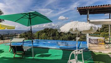 Una piscina con una cubierta verde, una sombrilla blanca y una estructura de techo de paja blanca.