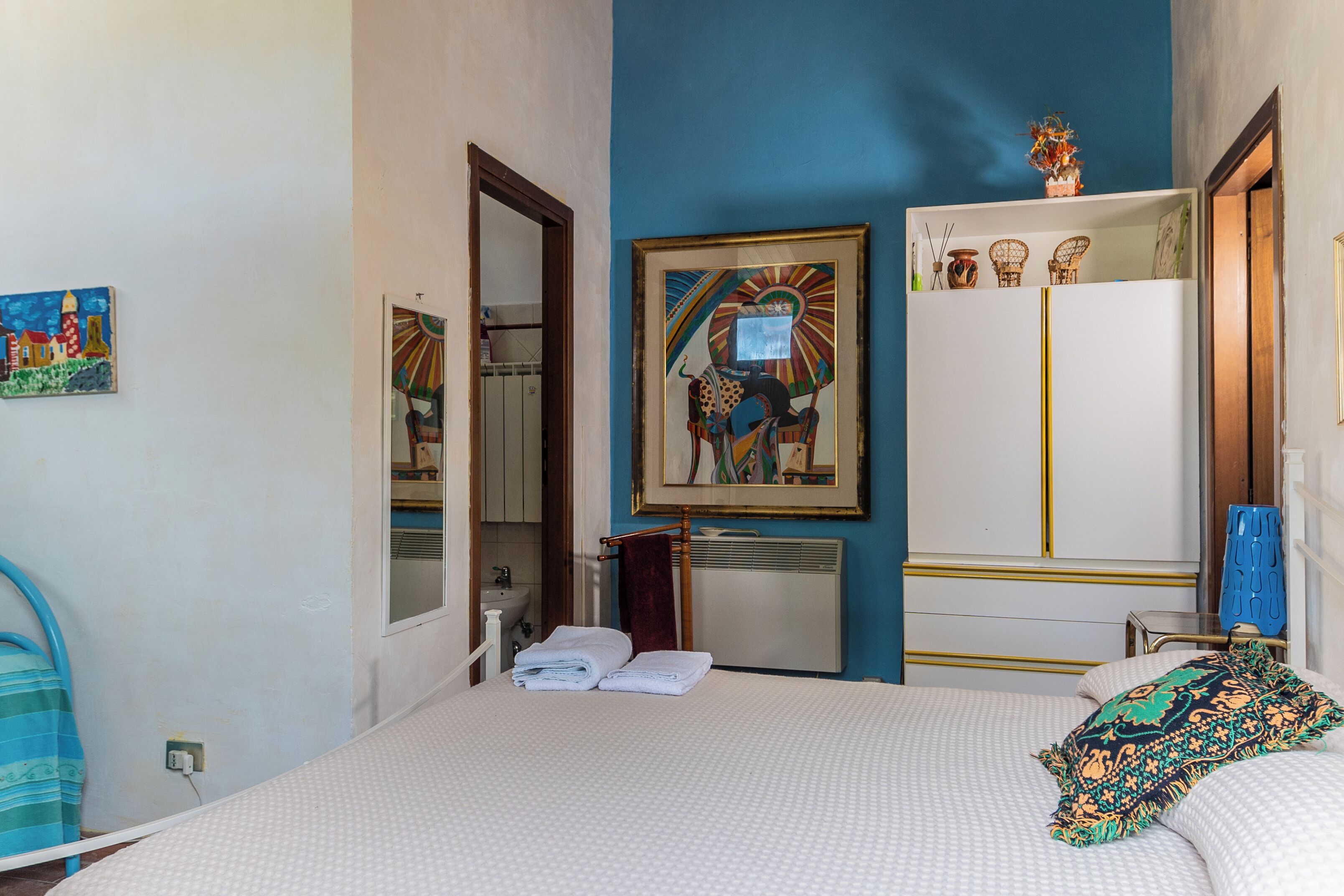 Una camera da letto con un letto, un armadio, uno specchio e un quadro appeso al muro.