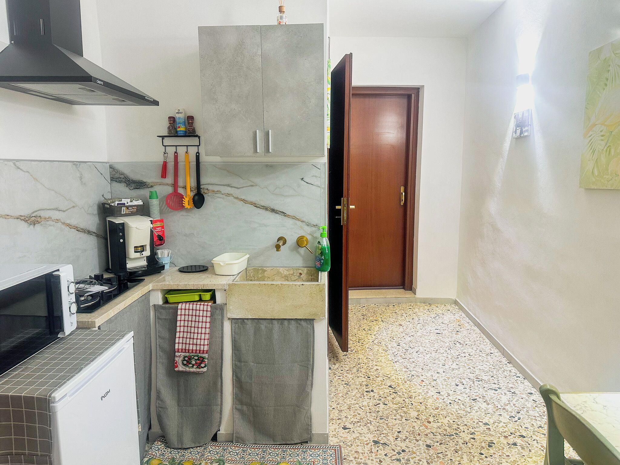 A compact kitchen with a gas stove, a coffee machine, and a refrigerator.
