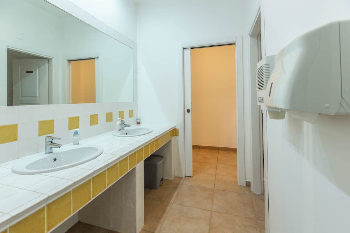 A bathroom with two sinks, a mirror, and a hairdryer on the wall.