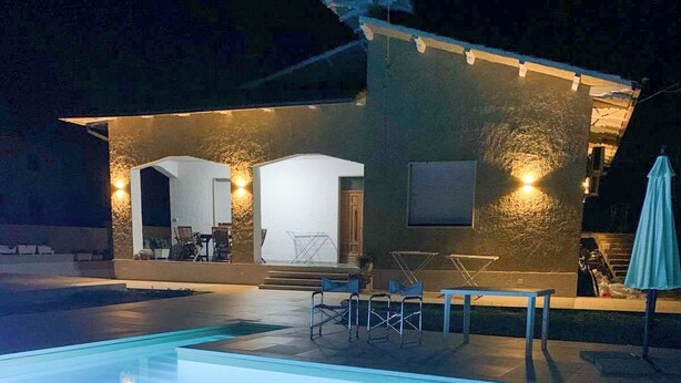 A swimming pool with a patio area, outdoor seating, and a building with a stone facade and warm lighting. - Villa D'Angelo (Casalbordino)