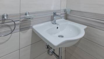 A bathroom with a white sink, chrome faucet, and towel rack.