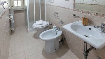 A bathroom with a toilet, bidet, and sink.