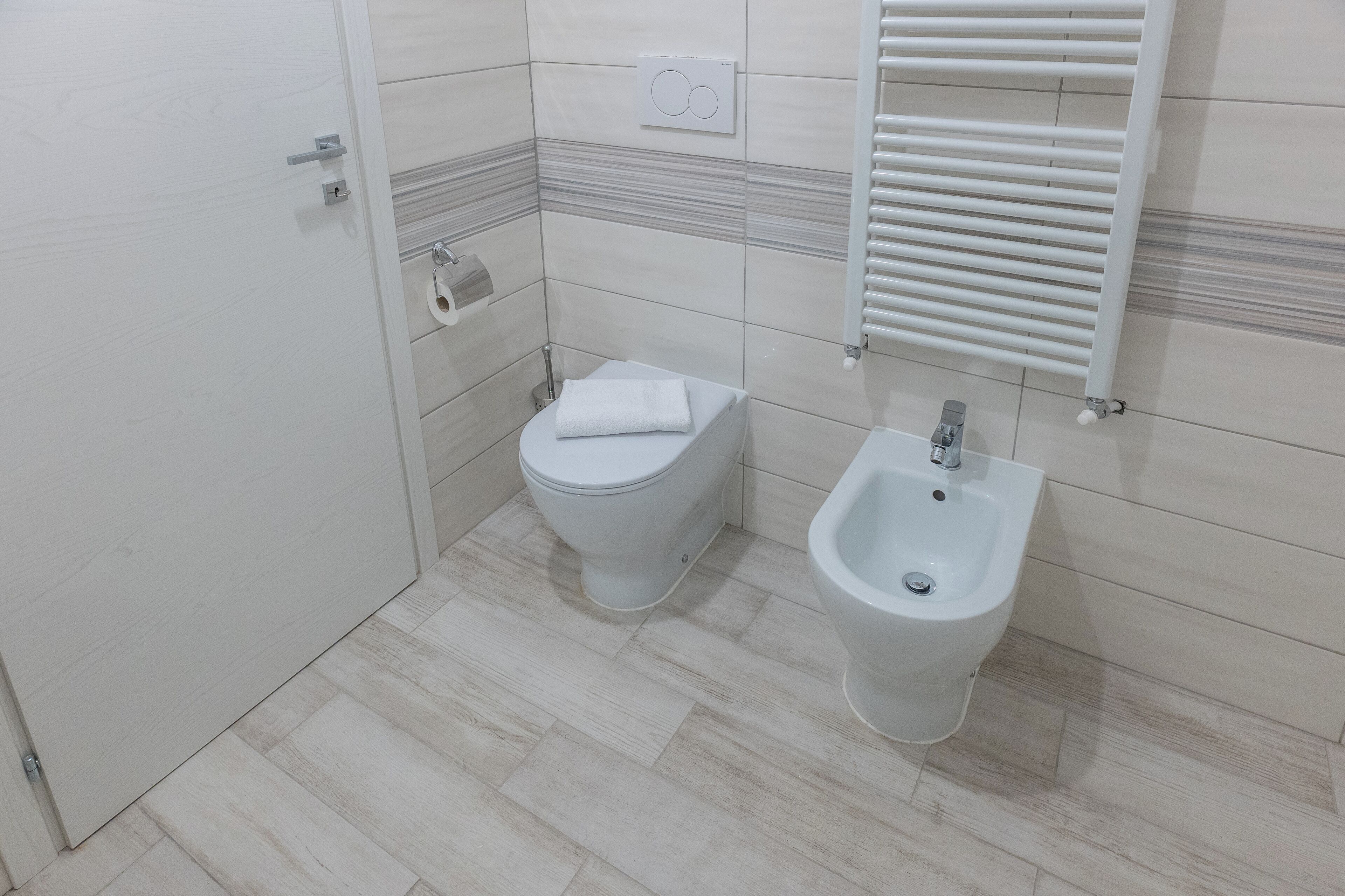 Une salle de bain équipée de toilettes, d’un bidet et d’un porte-serviettes.