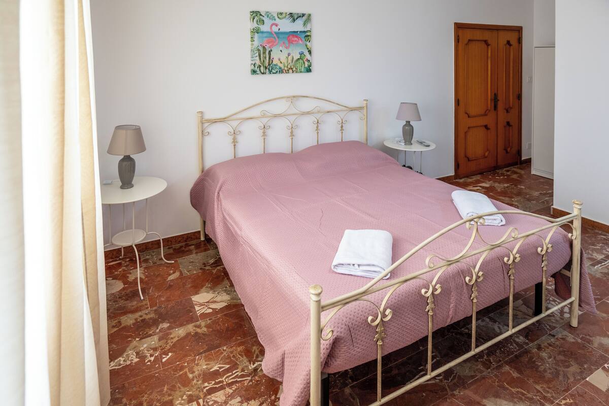 Une chambre à coucher avec un lit, une table de chevet, une lampe, un tableau et une porte en bois.