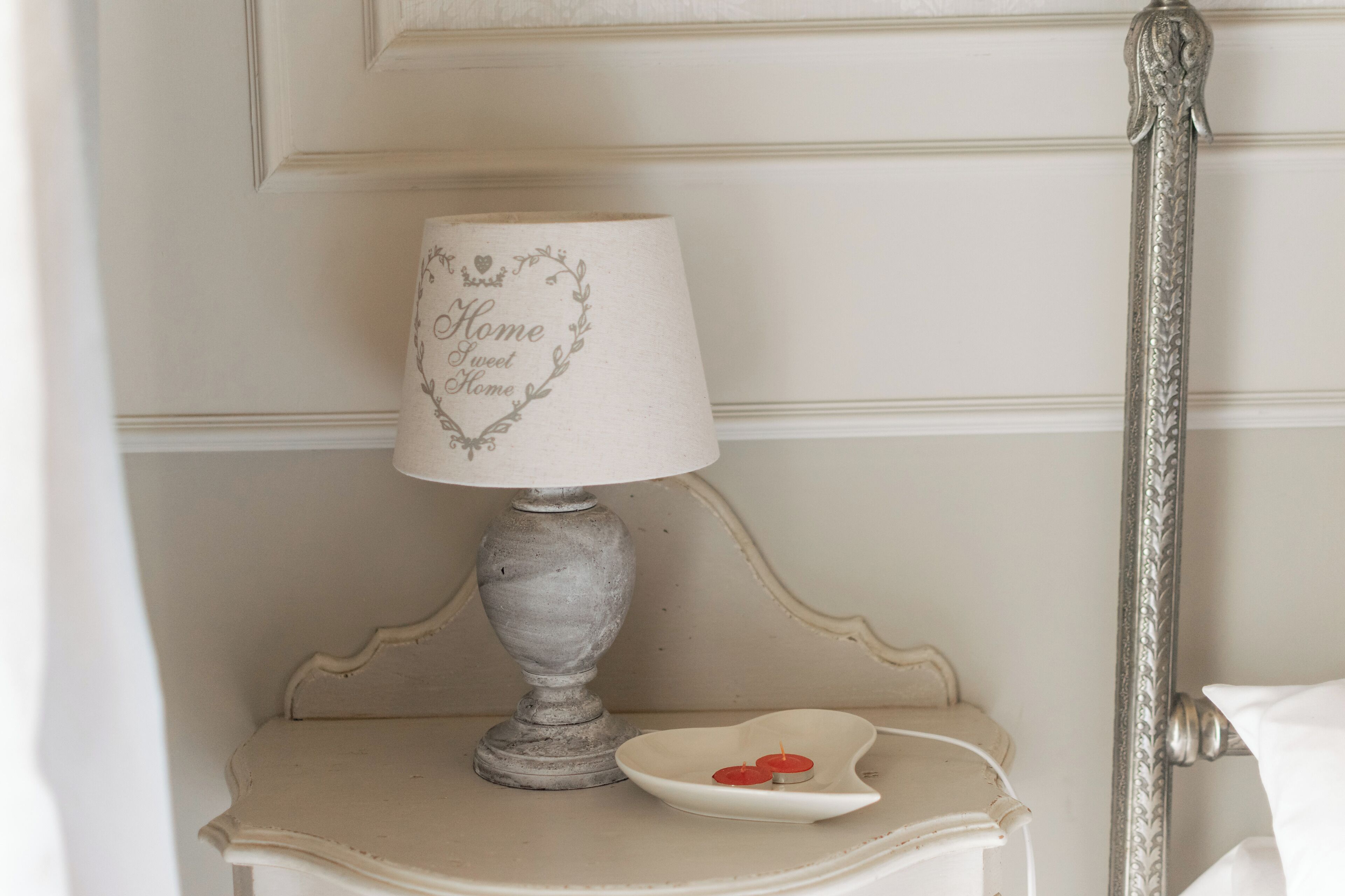 A bedside table with a lamp and a small dish with candles.
