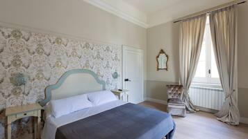 Un dormitorio con cama, mesita de noche, silla y ventana con cortinas.