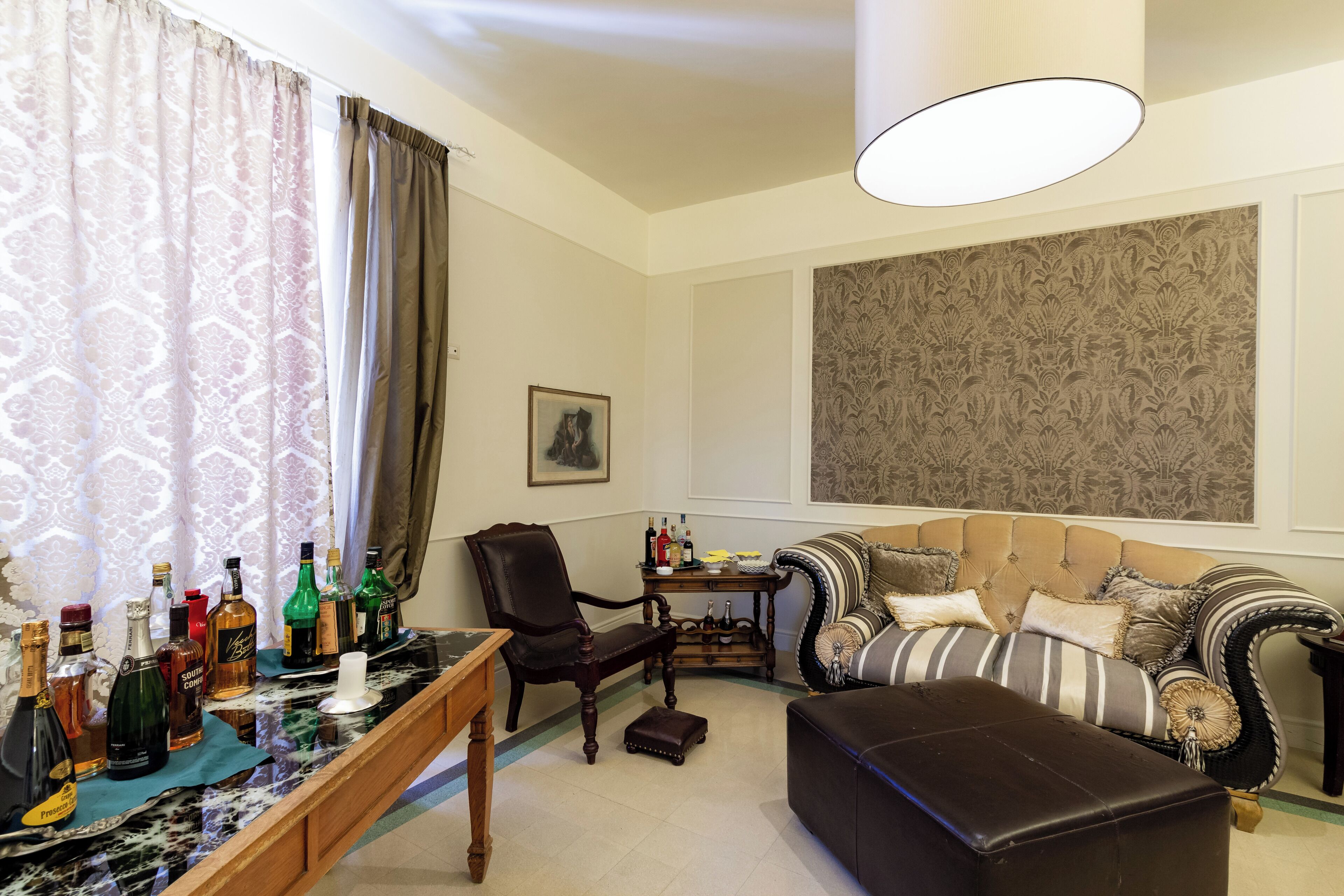 Una sala de estar con sofá, sillón, una mesa de centro y una zona de bar con botellas.