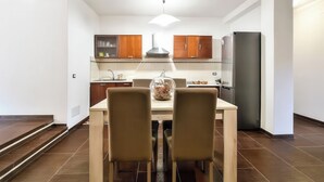 A modern kitchen with wooden cabinets, a stainless steel refrigerator, and a dining table with chairs. - B&B AniMo (Loceri)