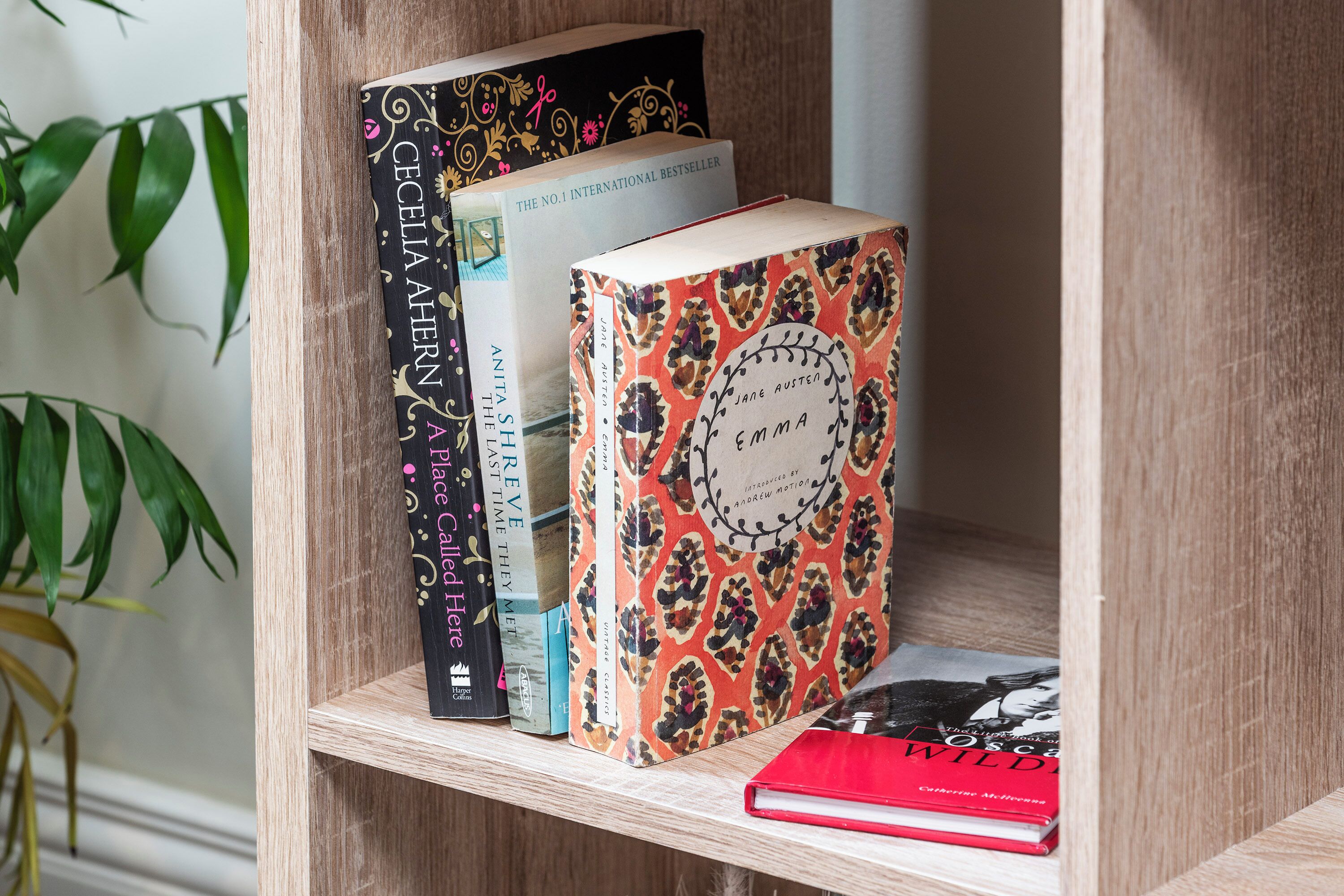 A bookshelf with books, including 'Emma' by Jane Austen, and a red book titled 'Wild'.